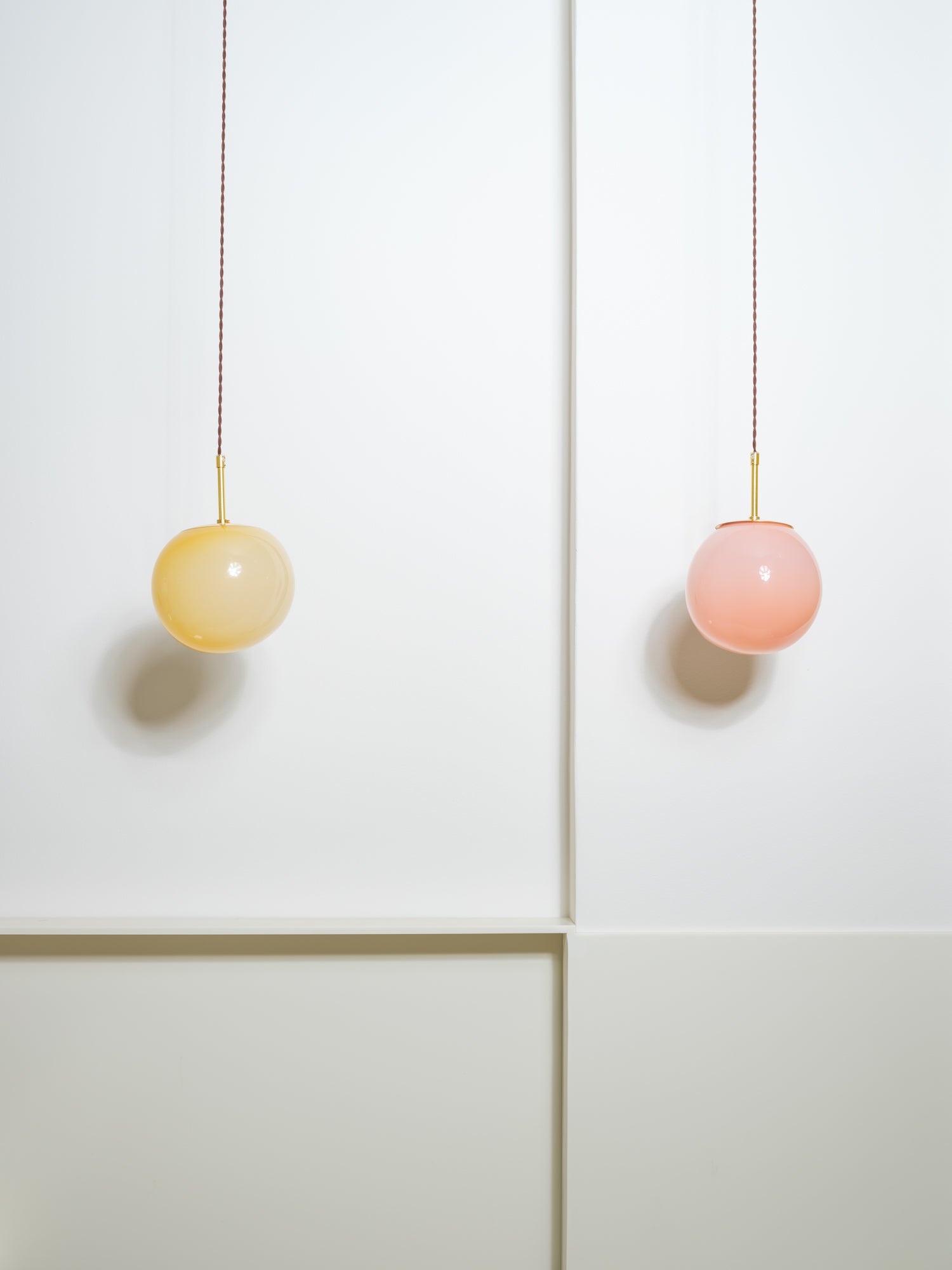 Two pendant lamps made of glass in light pink and light yellow